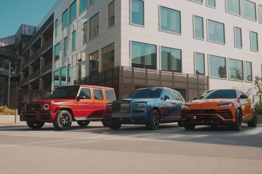 Three luxury SUVs parked on a street
